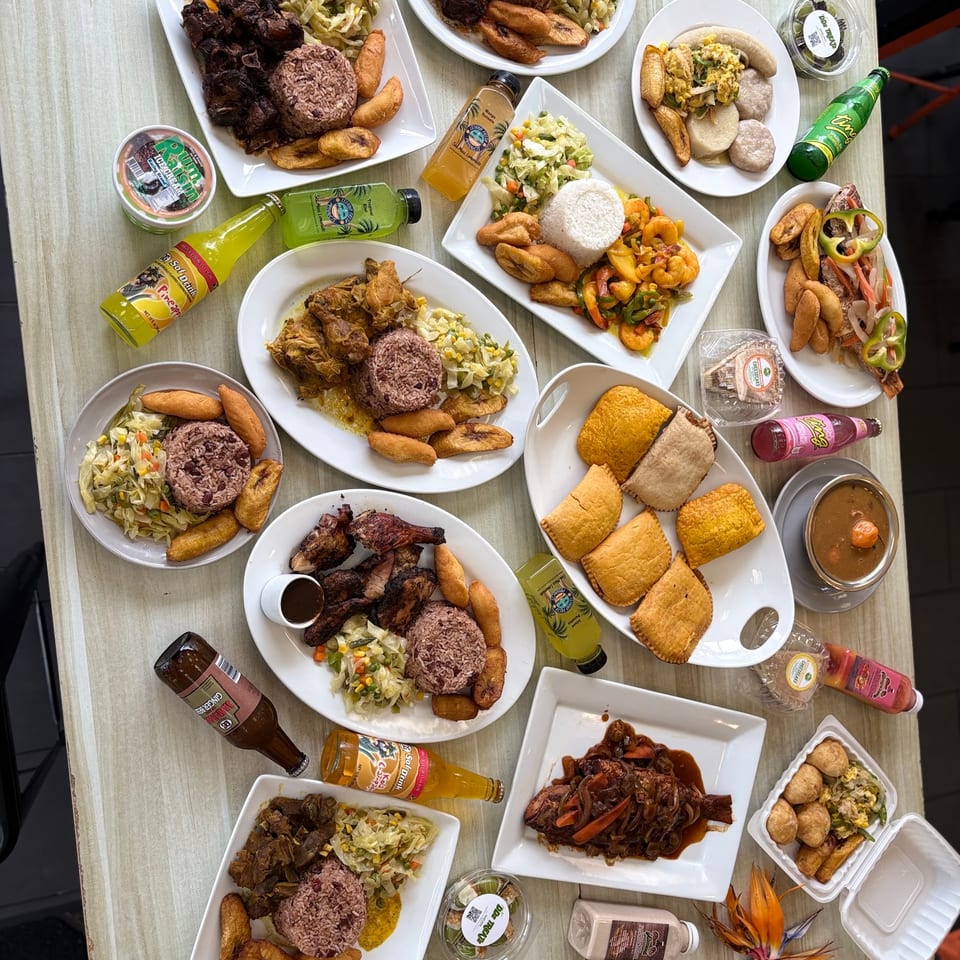 Overhead spread of Jamaican meals, sides and drinks.
